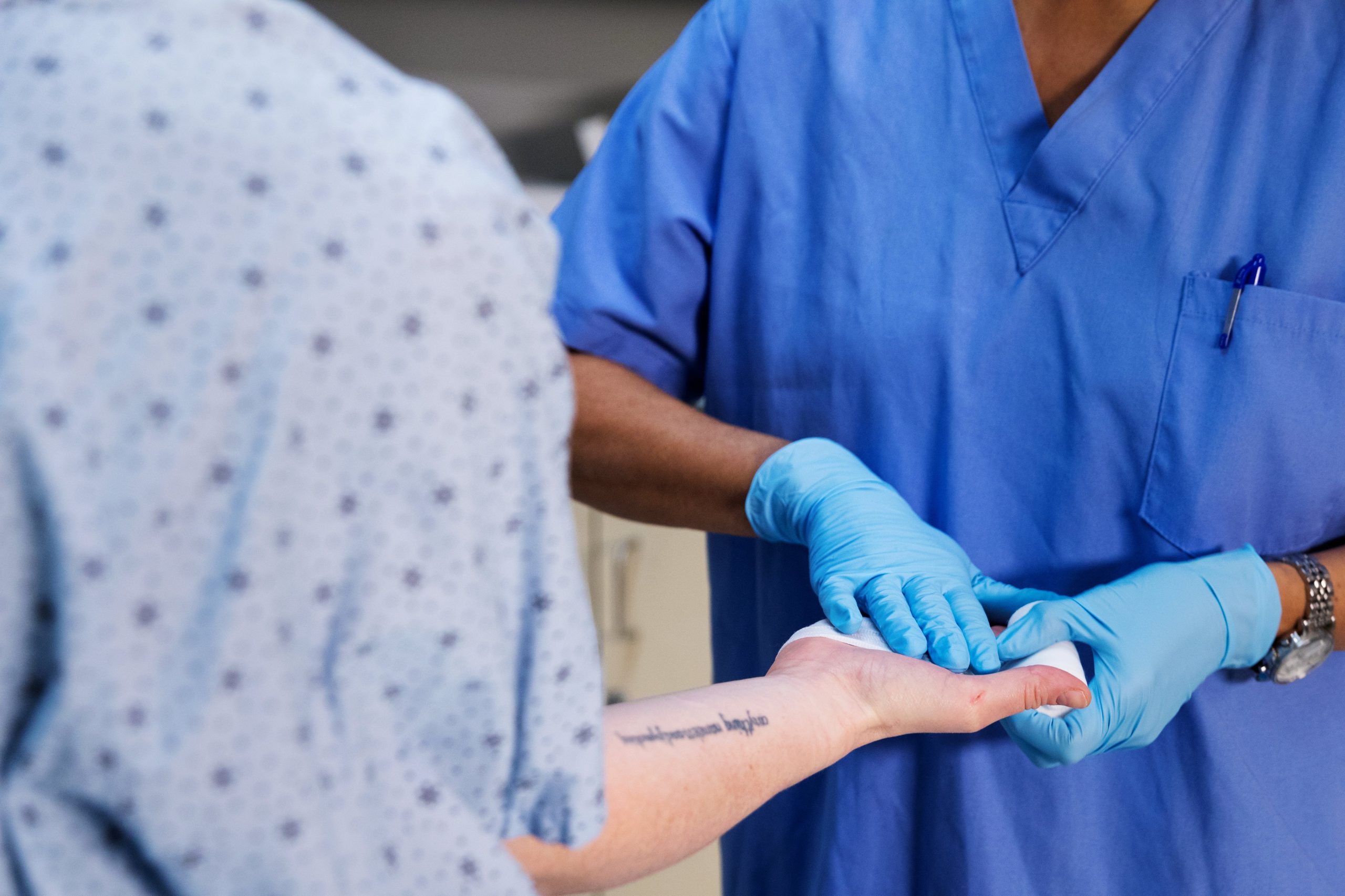 a nurse helping a patient who's hurt their hand and wrapping gauze