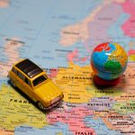 Colourful map of Europe with a small toy car placed on it
