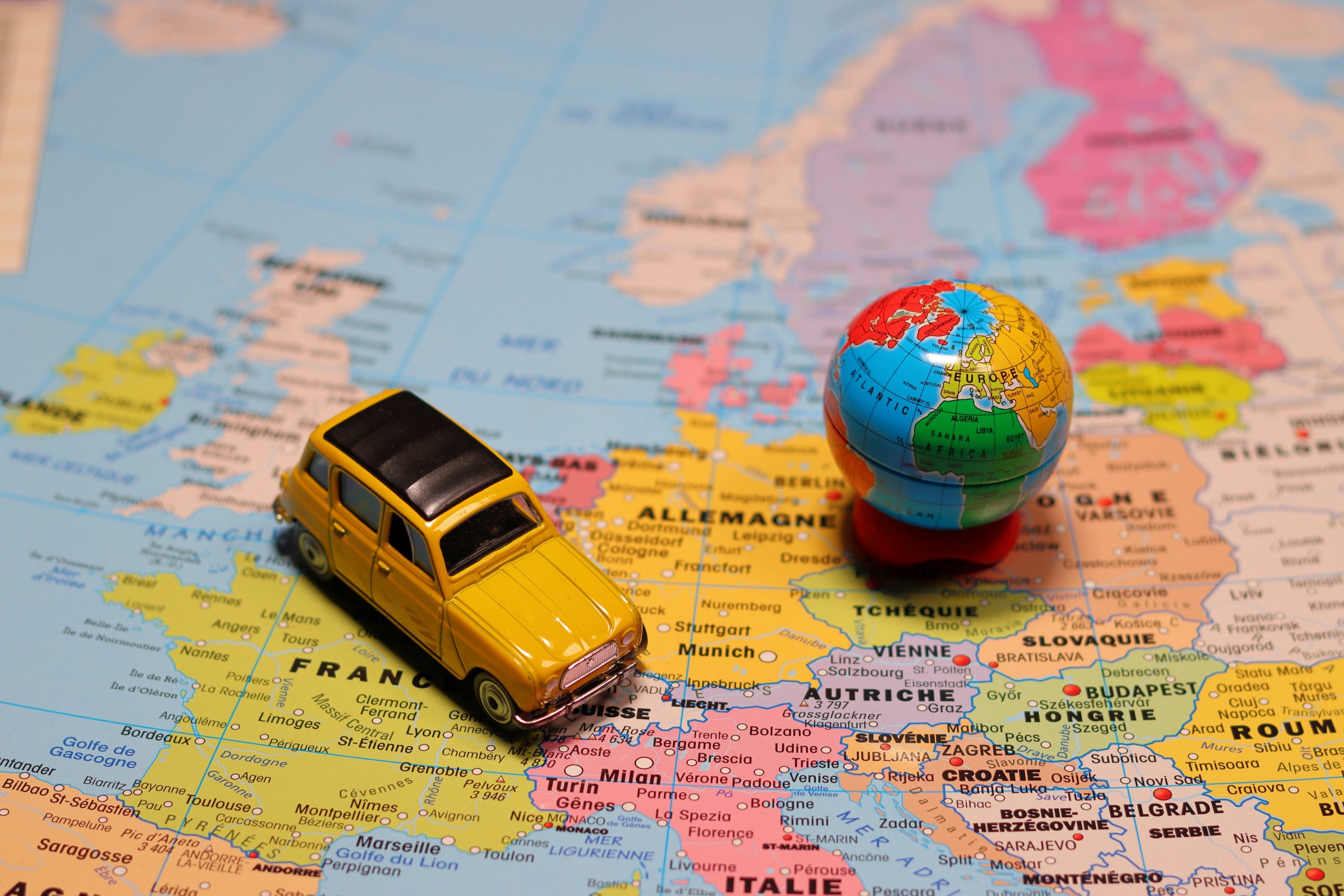 Colourful map of Europe with a small toy car placed on it