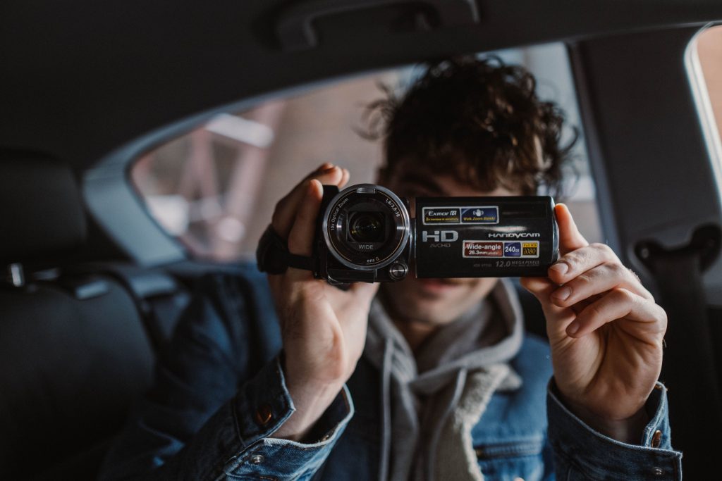 young person in a car holding a video camera