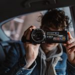 young person in a car holding a video camera