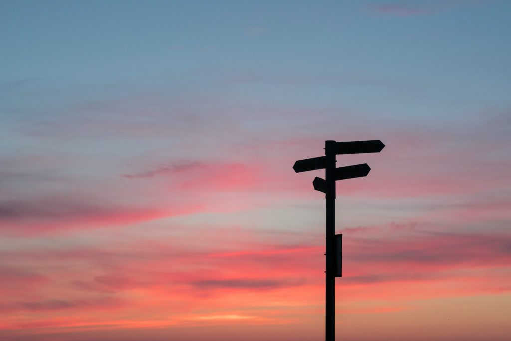 signpost silhouette against a sky at dusk