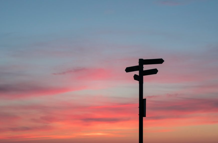 signpost silhouette against a sky at dusk